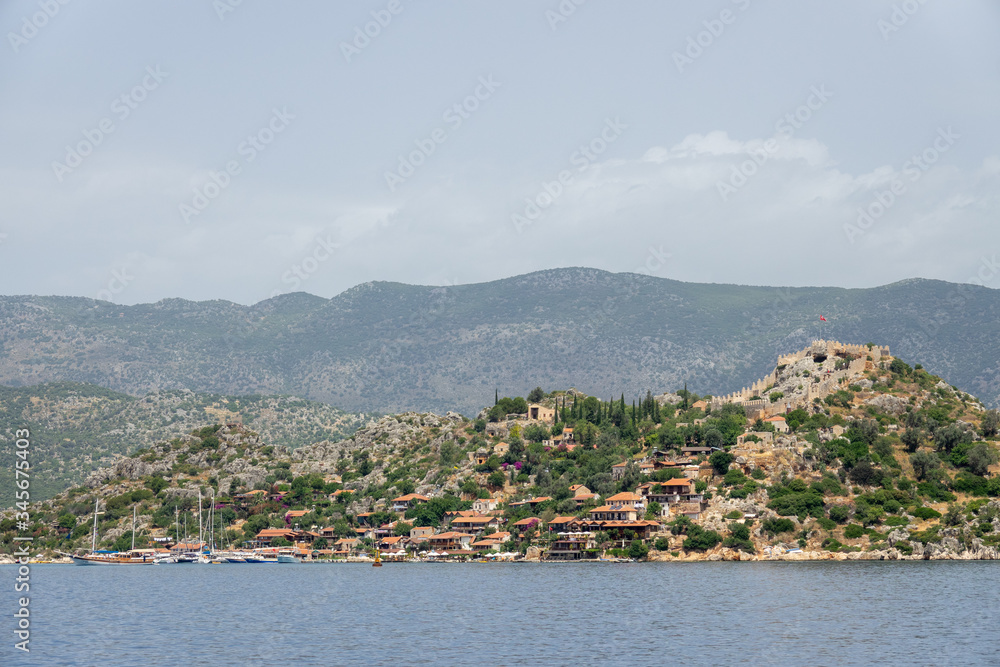Kalekoy village with stone built houses and castle on top of hill in Uchagiz bay in Turkey