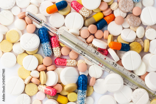 Thermometer and pills, medicine for pneumonia, antibiotics on an pink background. Coronavirus, MERS-CoV, Wuhan coronavirus 2019-nCoV,concept of Corona virus quarantine,Covid-19.