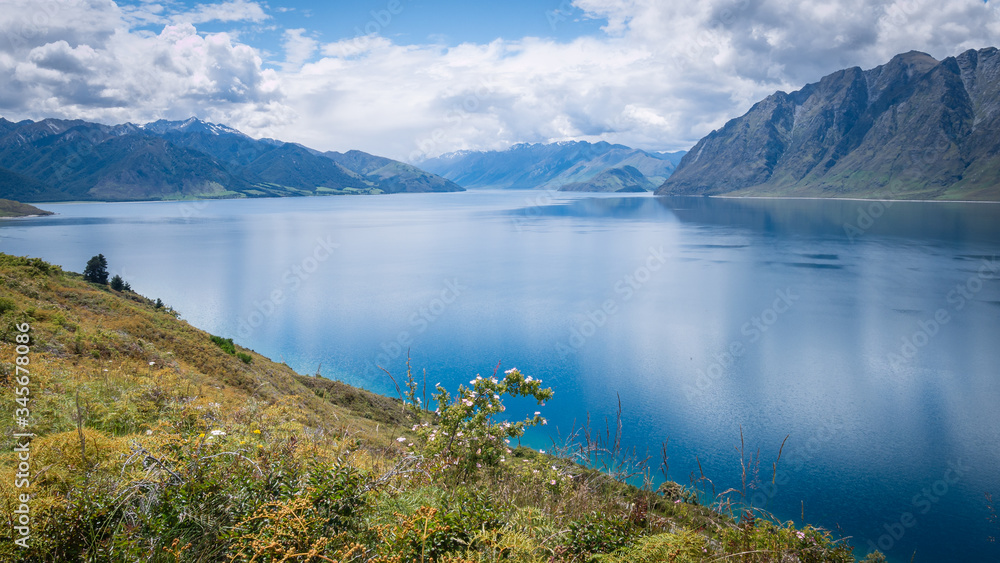 Scenic alpine lake surrounded by mountains shot on sunny day. Location is lake Hawea, New Zealand.
