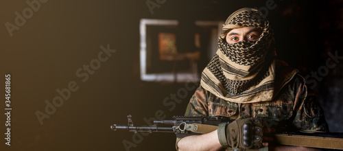 Arab male soldier in a headdress from the national keffiyeh with weapons in his hands. Muslim man with guns on black photo