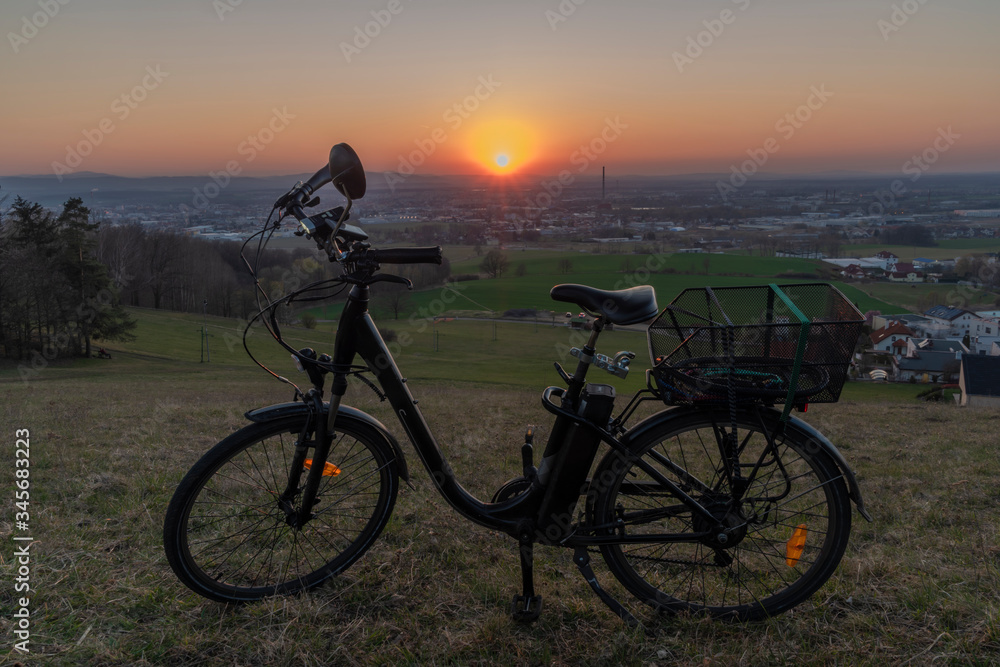 Black electric bike on ski slope in Budweis city with sunset Black electric bike on ski slope in Budweis city with sunset