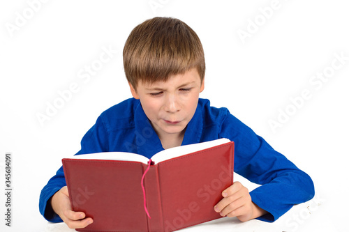 boy schoolboy in a blue t-shirt is preparing for school, carefully reading something in the book