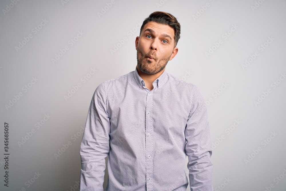 Young business man with blue eyes standing over isolated background making fish face with lips, crazy and comical gesture. Funny expression. Young business man with blue eyes standing over isolated background making fish face with lips, crazy and comical gesture. Funny expression.