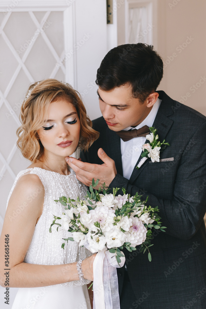 Bride and groom. Portrait of a man in a suit and a blonde woman in a white vintage dress in a classic interior on a wedding day. Bride and groom. Portrait of a man in a suit and a blonde woman in a white vintage dress in a classic interior on a wedding day.