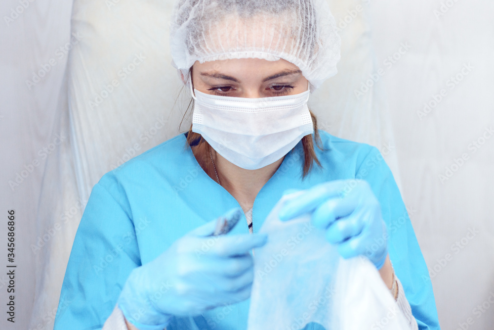 Girl in mask and medical gown with nail file and cuticle nippers in hands, salon worker, manicure and pedicure master