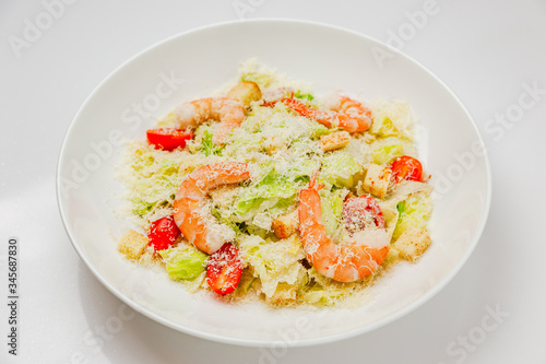 Caesar salad with prawns on a white plate