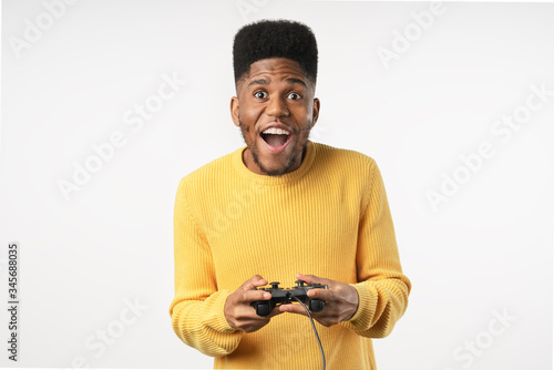 Obraz na płótnie Afro gamer man playing video game using joystick over isolated white background
