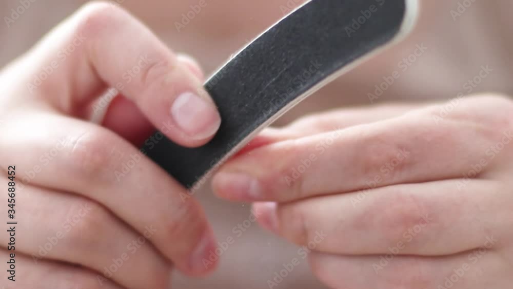 Close up of female performing a manicure on herself using a nail file Close up of female performing a manicure on herself using a nail file