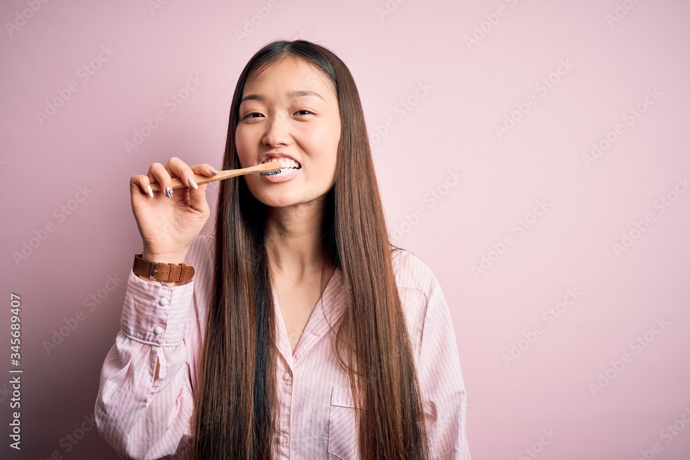 Young beautiful asian woman wearing pajama brushing her teeth using tooth brush and oral paste, cleaning teeth and tongue as healthy health care morning routine Young beautiful asian woman wearing pajama brushing her teeth using tooth brush and oral paste, cleaning teeth and tongue as healthy health care morning routine