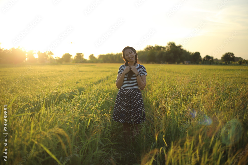 Fototapeta premium A woman standing in a rice field in Rayong, Thailand