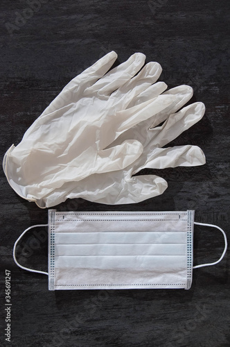 Disposable medical mask and rubber gloves with grey background, top view. Virus protection kit.