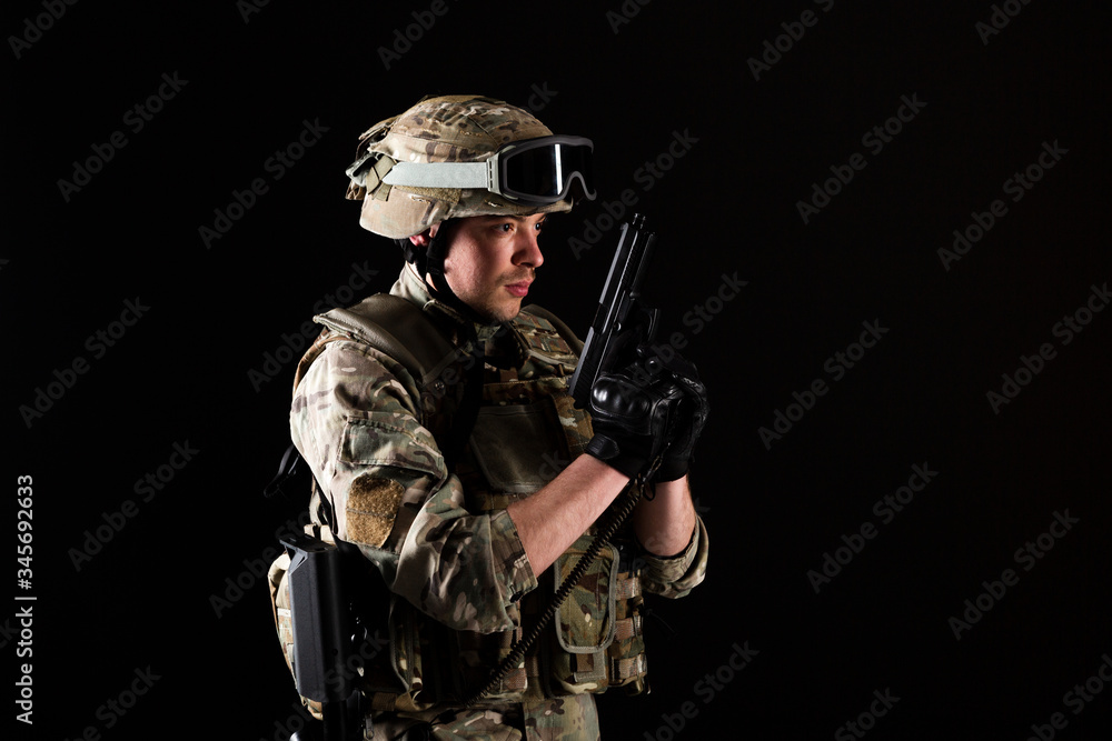 Soldier with gun is on mission on black background. Concept of war.