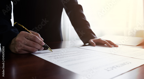 Fotografie Close up businessman or manager signing documents contract paper, lease mortgage, partnership agreement, employment with a pen making the signature , Horizontal Vintage sunlight background