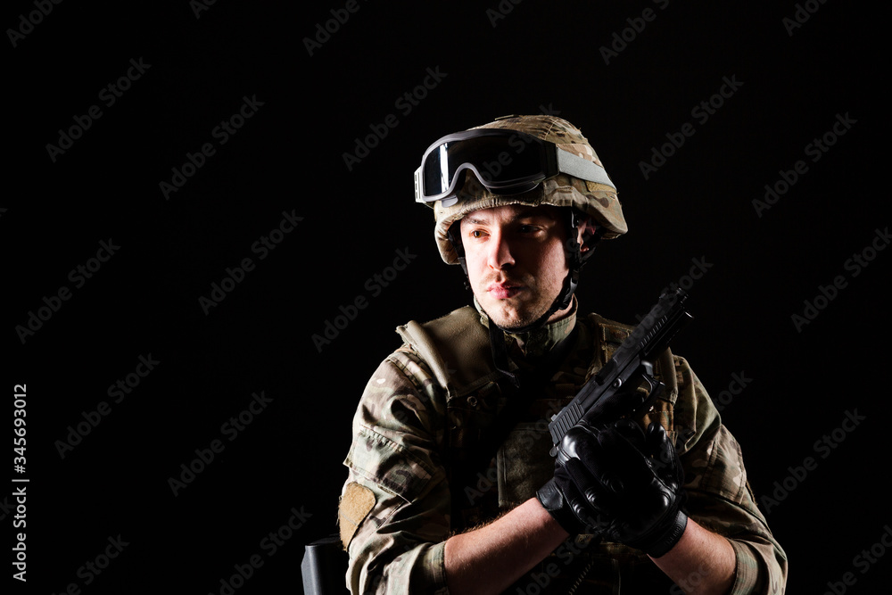 Fototapeta premium Soldier with gun is on mission on black background. Concept of war.
