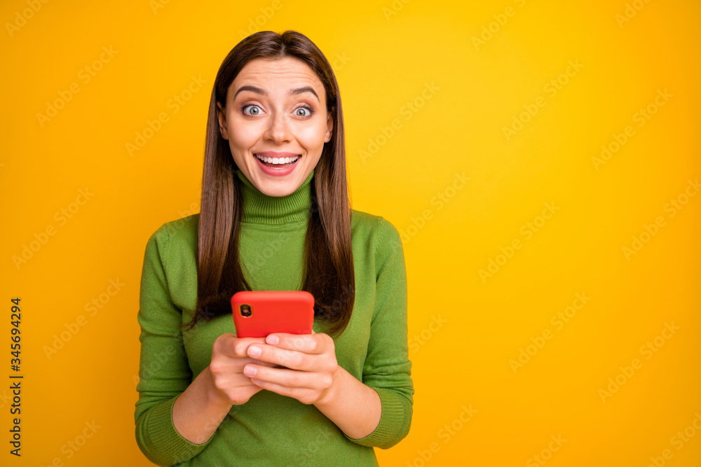Portrait of amazed excited girl using her cellphone get social media notification scream wow omg wear good looking outfit isolated over yellow color background Portrait of amazed excited girl using her cellphone get social media notification scream wow omg wear good looking outfit isolated over yellow color background