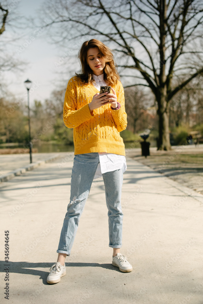 Young brunette woman using phone in city park. Young brunette woman using phone in city park.