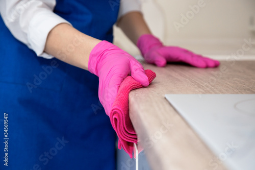 Girl in pink rubber gloves washes the kitchen.