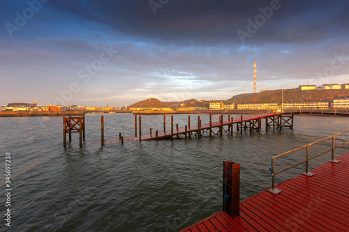 Heligoland - harbor with pier and colorful houses at sunrise with dramatic sky.