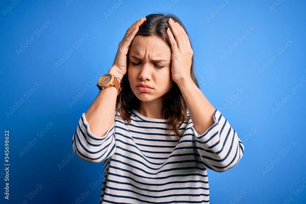 Young beautiful blonde girl wearing casual sweater standing over blue isolated background suffering from headache desperate and stressed because pain and migraine. Hands on head. Young beautiful blonde girl wearing casual sweater standing over blue isolated background suffering from headache desperate and stressed because pain and migraine. Hands on head.