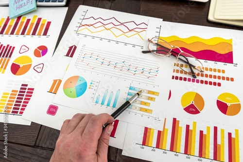 Male hand showing diagram or chart on financial report with pen