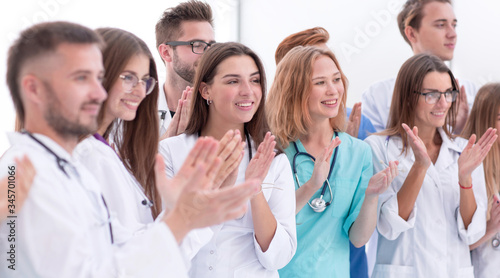 close up. a group of different doctors applauds together.
