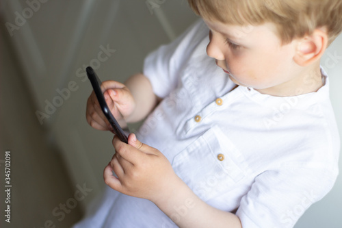 the child is holding a phone in his hand with a black screen. Communication via video communication