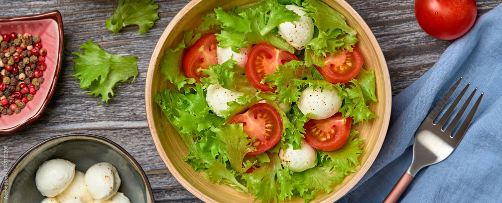 Fresh salad with cherry tomatoes, mozzarella cheese, greens leaves in bowl. Summer salad vegetarian meal concept. Tomatoes and lettuce homemade caprese salad on wood, banner Fresh salad with cherry tomatoes, mozzarella cheese, greens leaves in bowl. Summer salad vegetarian meal concept. Tomatoes and lettuce homemade caprese salad on wood, banner