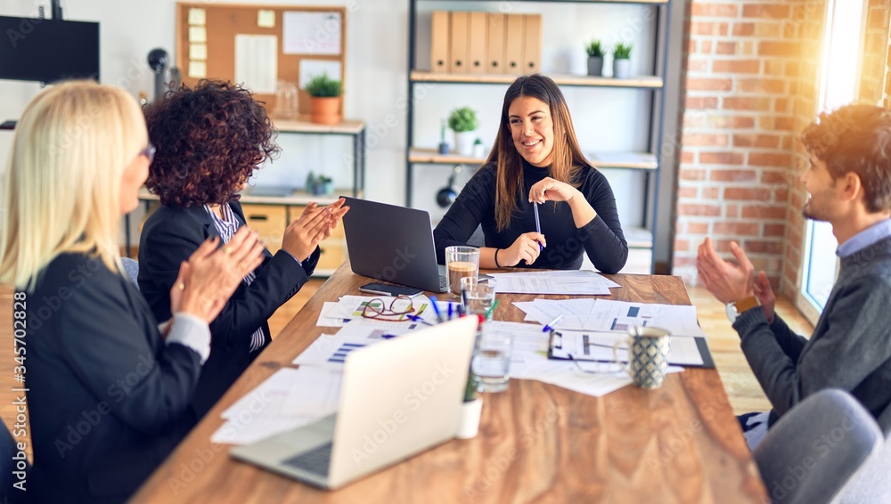Group of business workers smiling happy and confident. Working together with smile on face applauding one of them at the office Group of business workers smiling happy and confident. Working together with smile on face applauding one of them at the office
