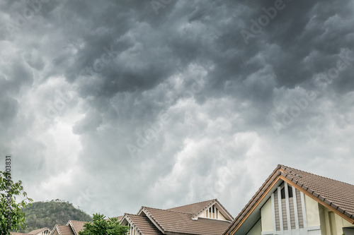 Dark clouds going to heavy rain over the house roof.