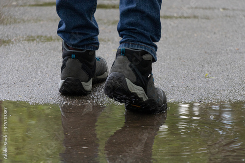 A man walks through puddles. Rainy day. Wet asphalt.