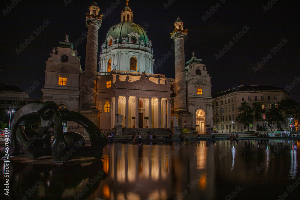 An evening gathering for both locals and tourists at the reflecting pool outside of St. Charles Church in Vienna, Austria