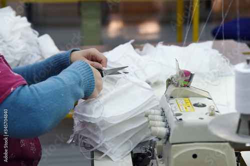 A woman cuts gauze masks with scissors.