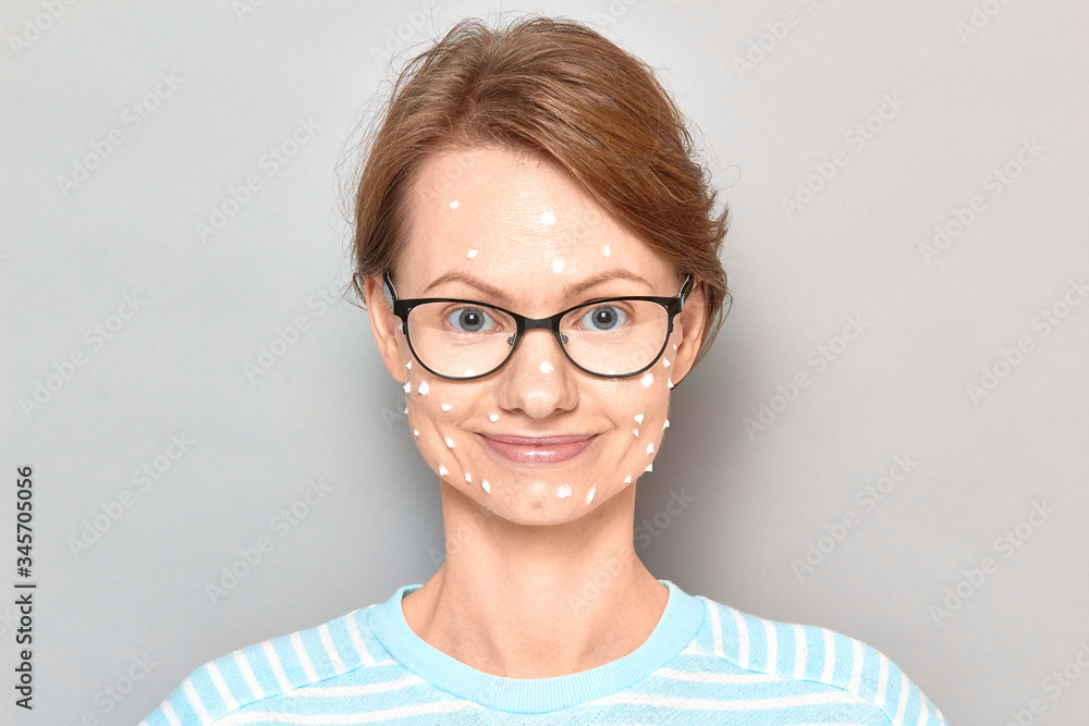 Portrait of happy girl with white drops of face cream on skin Portrait of happy girl with white drops of face cream on skin