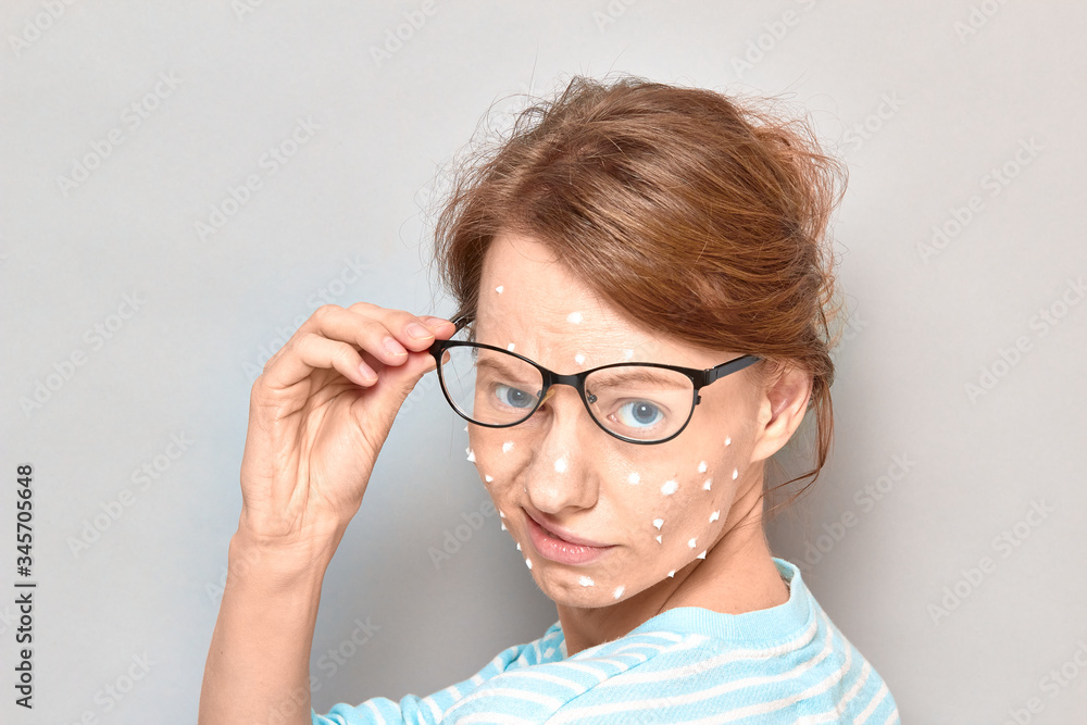 Portrait of annoyed girl with white drops of face cream on skin