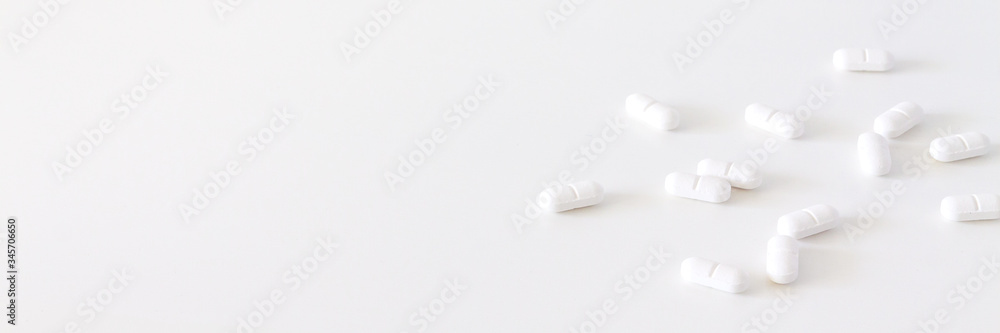 White scattered pills on a white background. Copys space. Panorama White scattered pills on a white background. Copys space. Panorama