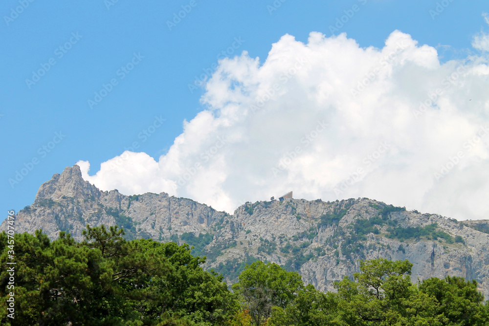 forest and mountains against the blue sky and white clouds
