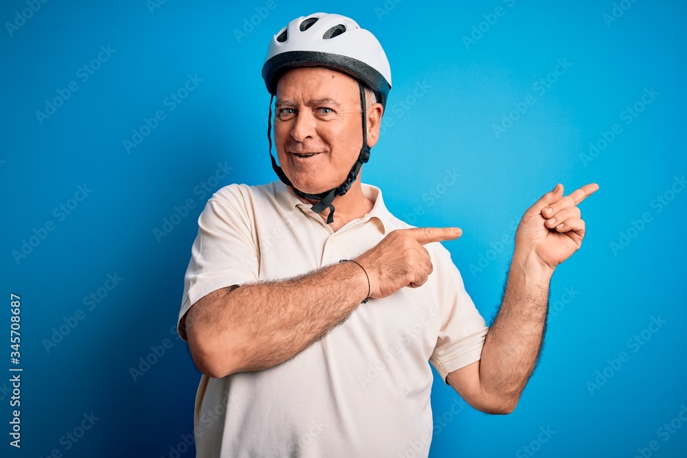 Middle age hoary cyclist man wearing bike security helmet over isolated blue background smiling and looking at the camera pointing with two hands and fingers to the side. Middle age hoary cyclist man wearing bike security helmet over isolated blue background smiling and looking at the camera pointing with two hands and fingers to the side.
