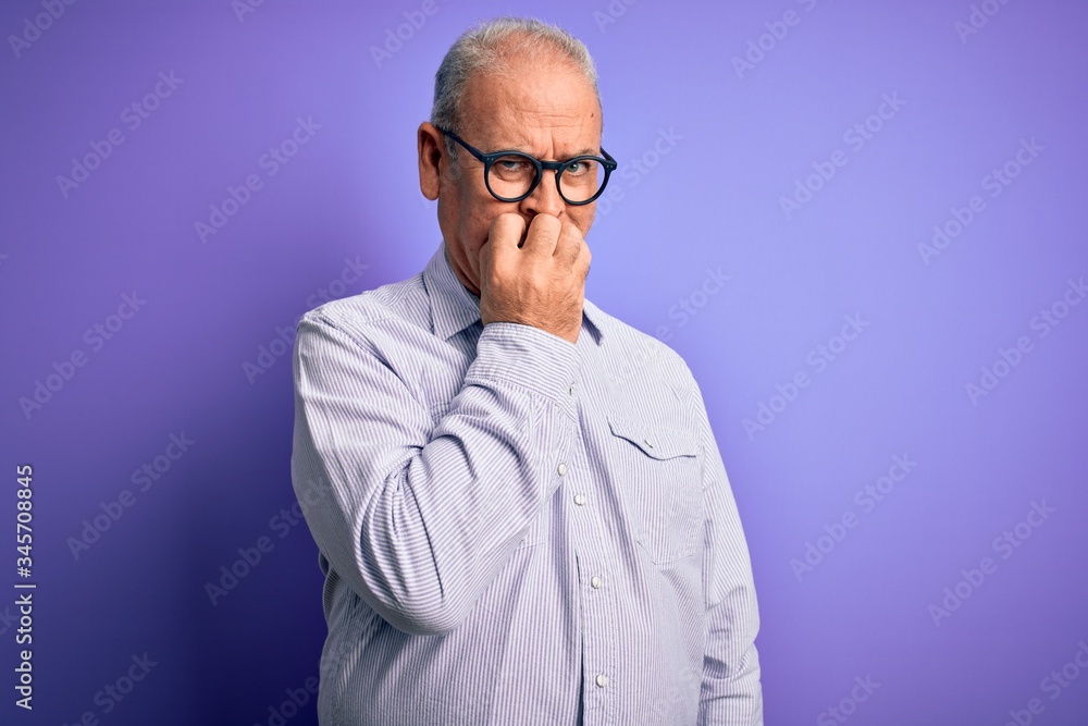 Middle age handsome hoary man wearing striped shirt and glasses over purple background looking stressed and nervous with hands on mouth biting nails. Anxiety problem.