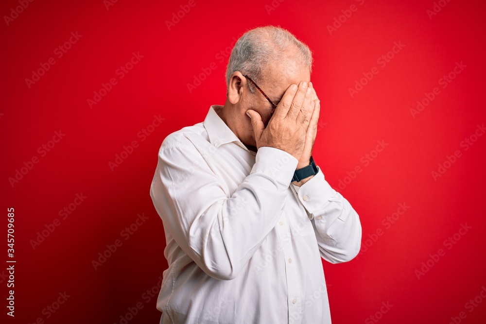 Middle age handsome hoary man wearing casual shirt and glasses over red background with sad expression covering face with hands while crying. Depression concept. Middle age handsome hoary man wearing casual shirt and glasses over red background with sad expression covering face with hands while crying. Depression concept.