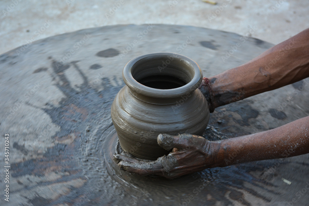 Hands working on pottery wheel and making a pot