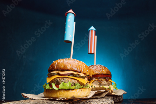 close up Image of two beef burgers with fireworks rockets. picnic festive snack on the fourth of july independence day