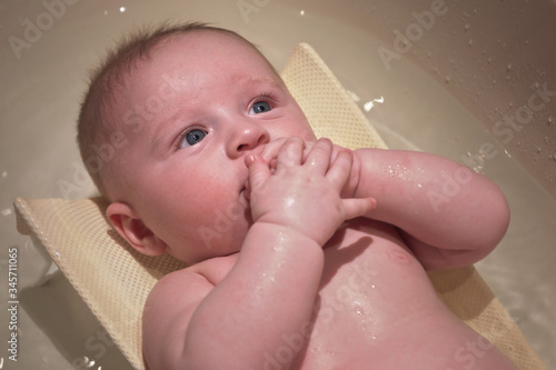 Infant baby boy washed in small bath tub, view from above