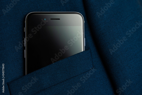 Black smartphone in men suit pocket close up.