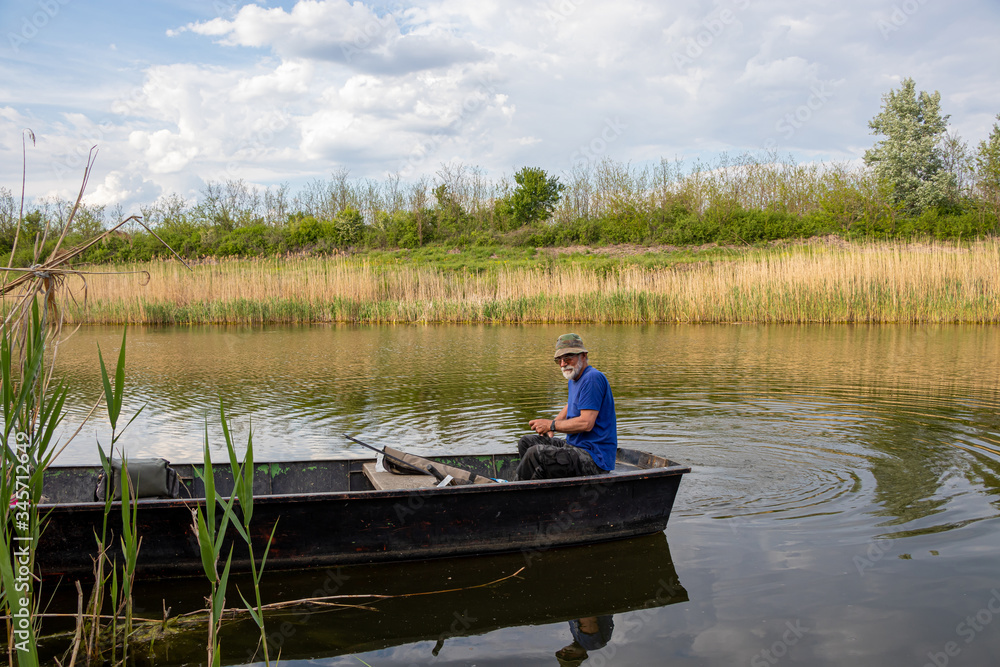 Senior fisherman in a boat at Danube-Tisa-Danube channel near Novi Sad, Serbia.