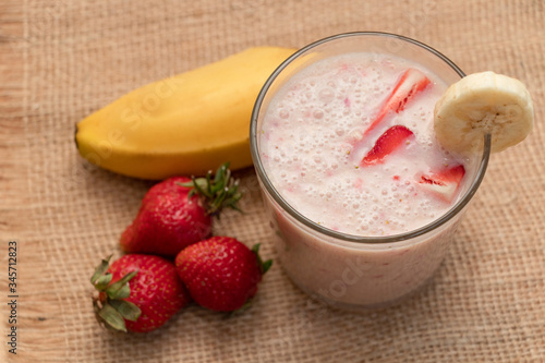 Banana Strawberry Milkshake. Glass cup on a wooden background. Homemade.