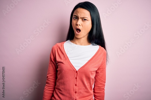 Young beautiful chinese woman wearing casual sweater over isolated pink background In shock face, looking skeptical and sarcastic, surprised with open mouth