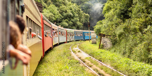 Pessoas viajando em um trem com vagões coloridos no meio da floresta. Maria fumaça em trilhos antigos no meio da vegetação. photo