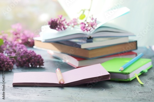Books, open notebook for notes, lilac flowers on the table, the concept of home schooling, comfortable at home, for education