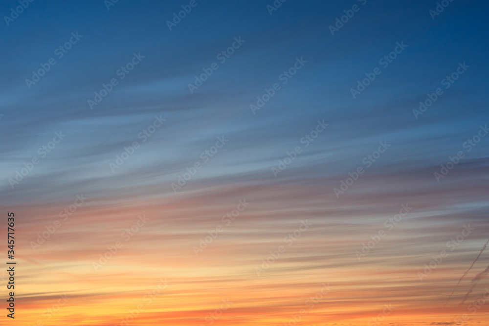 the sky with stripes during dawn is blue and orange.