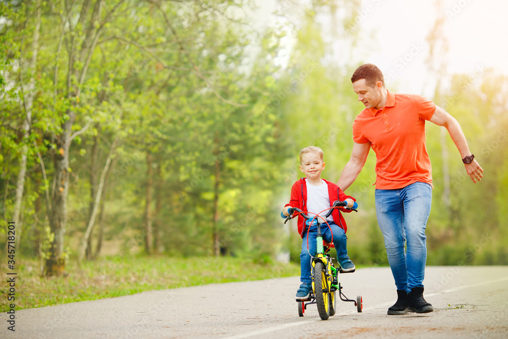 Obraz premium Happy father teaching his little son to ride bicycle. Child learning bike with dad